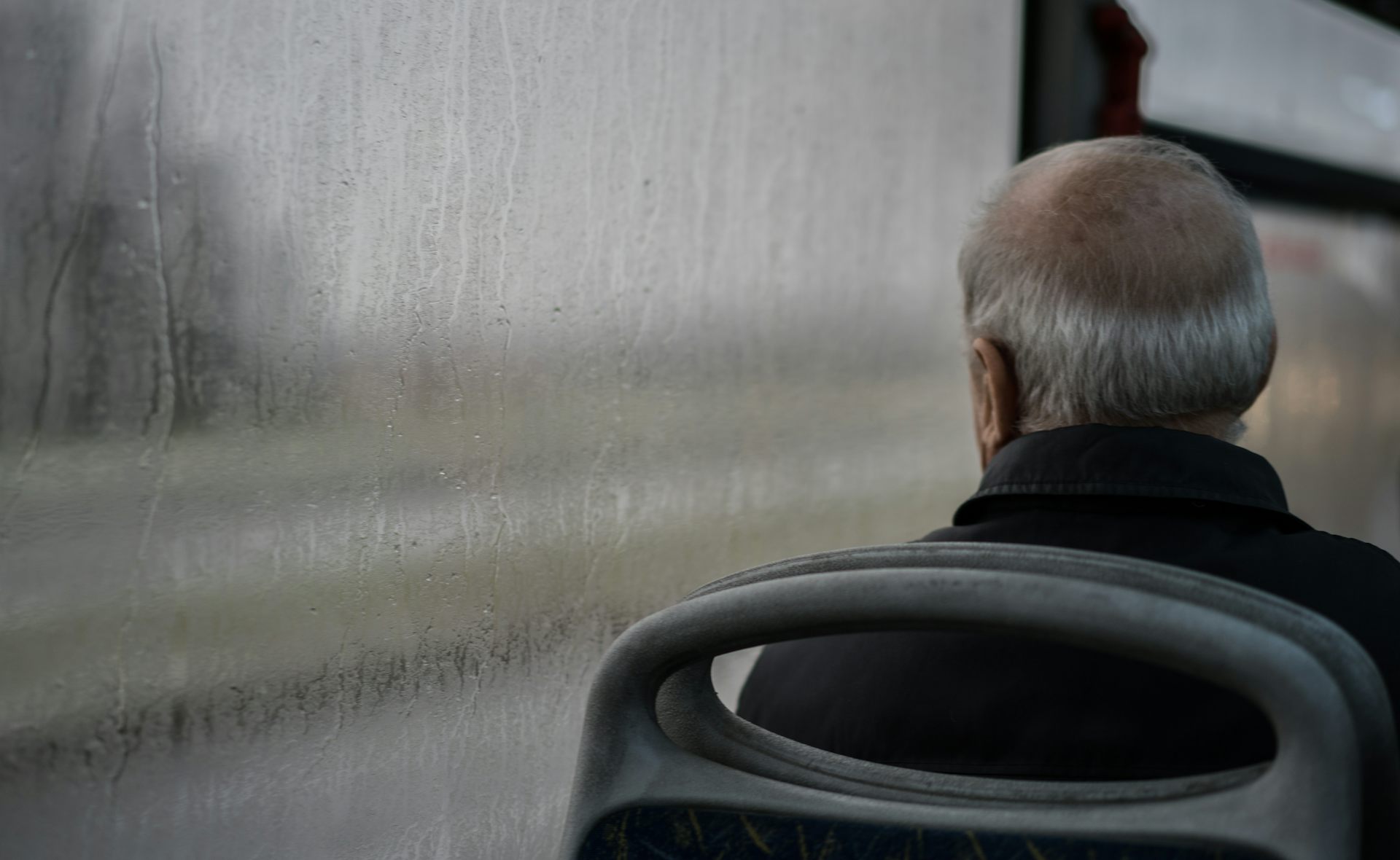 Older man on a bus looking out the window